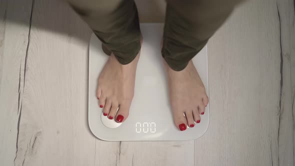 Young Woman Stands on a White Electronic Scale