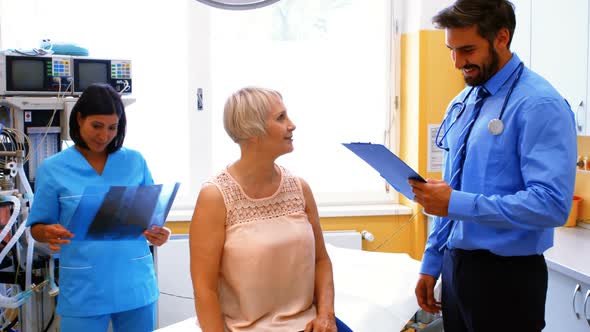 Male doctor interacting with a patient while nurse looking at x-ray