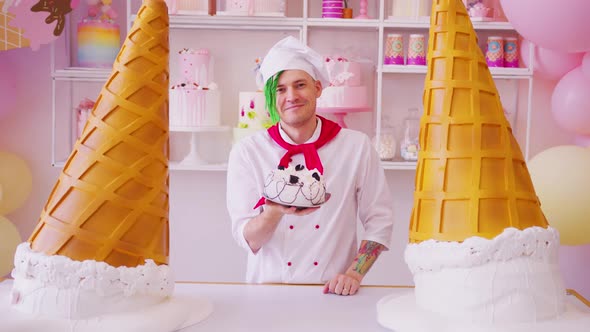 Young Man Dressed As Chef with Cake Standing in Bright Confectionery