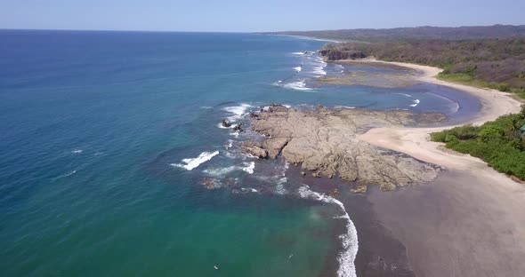 Aerial drone view of the beach, rocks and tide pools in Playa Palada, Guiones, Nosara, Costa Rica.