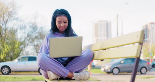 Asian Woman Freelancer Outdoors Working on Laptop alt