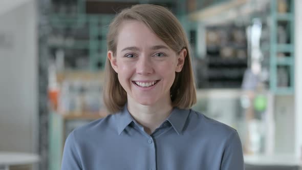 Portrait of Attractive Young Woman Smiling at Camera in Cafe