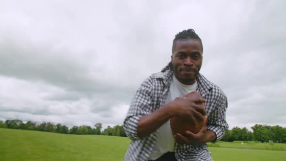 Active African Man with American Football Gaining Yards During Game