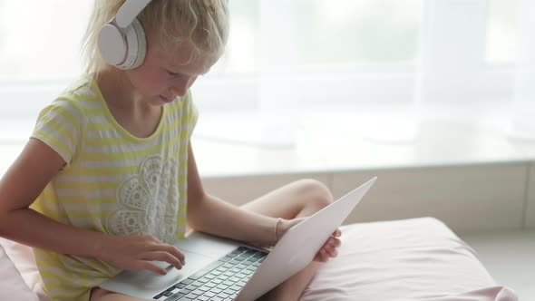 Blonde Schoolgirl Studying on Bed at Home Doing School Homework with Laptop