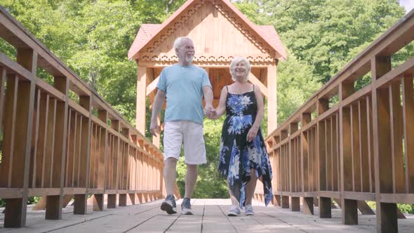 Happy Mature Couple Walking on the Bridge Holding Hands