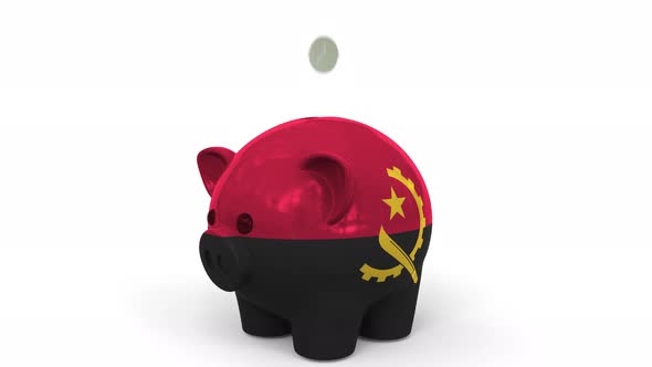 Coins Fall Into Piggy Bank Painted with Flag of Angola