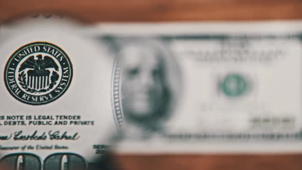 One Hundred Dollars Look Under Magnifying Glass on Wooden Table