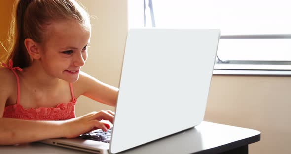 Schoolgirl using laptop in classroom at school