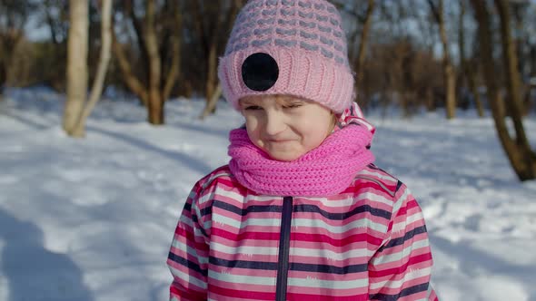 Child Girl Looking at Camera Starting Laughing Fooling Around Smiling in Winter Snow Park Forest