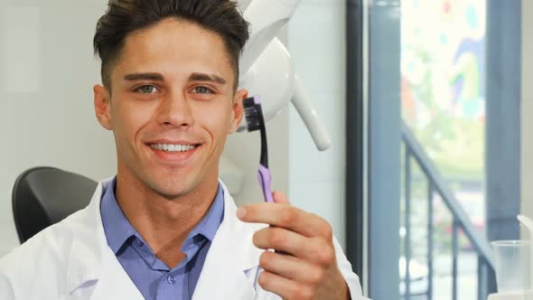 Attractive Male Dentist Smiling Holding a Toothbrush 1080p