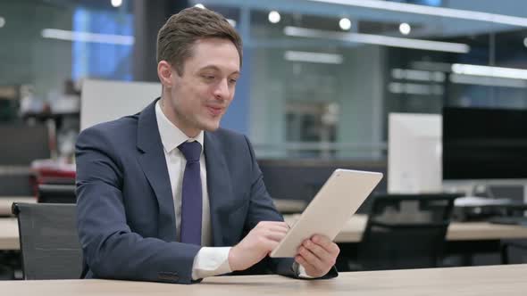 Businessman Celebrating Success on Tablet in Office Sitting