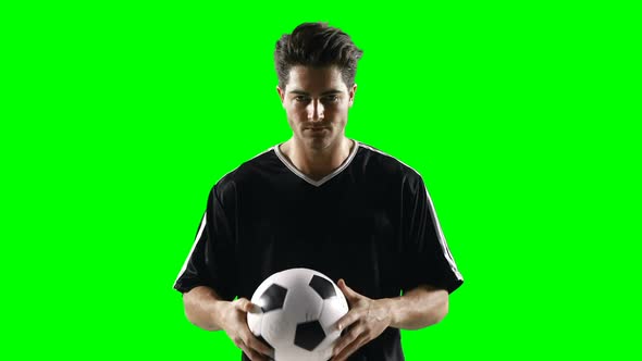 Football player holding a football against green screen