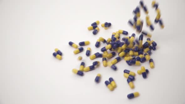 Slow Motion of Blue and Yellow Pills Dropped onto White Background