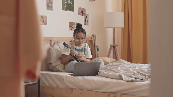 Asian Teenage Girl Learning to Play Ukulele at Home