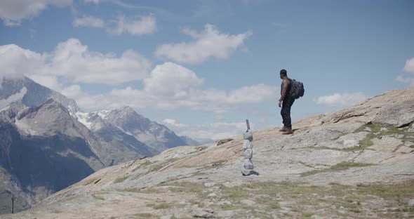 Black male traveler with backpack thinking about GOD and crossing himself while looking up mountains