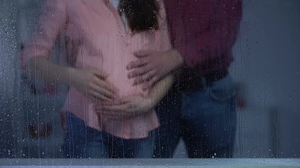 Couple Stroking Pregnant Woman Tummy Behind Rainy Window, Baby Expectation
