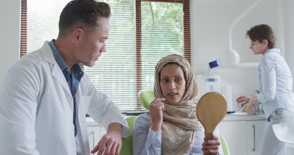 Caucasian male dentist talking with female patient at modern dental clinic