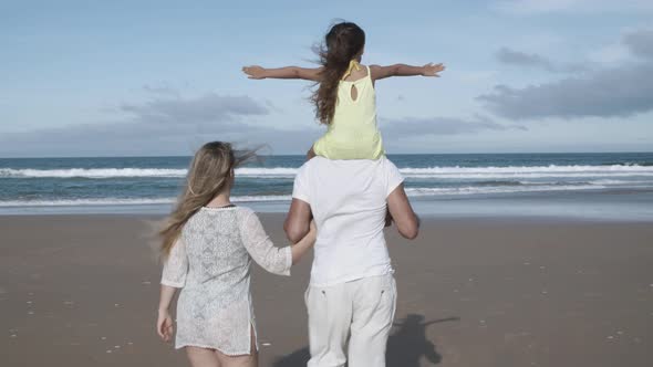 Parents Couple with Little Daughter Walking on Beach