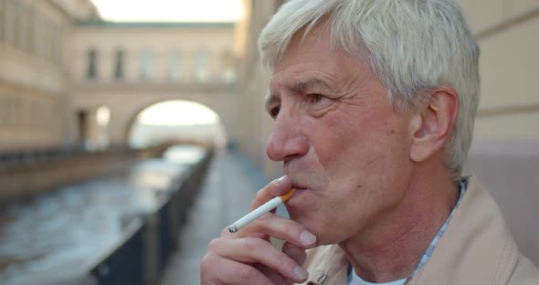 Senior Man Smoking Cigarette Outdoors in City