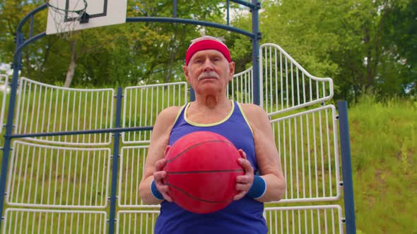 Senior Old Man Grandfather Athlete Posing Playing with Ball Outdoors on Basketball Playground Court