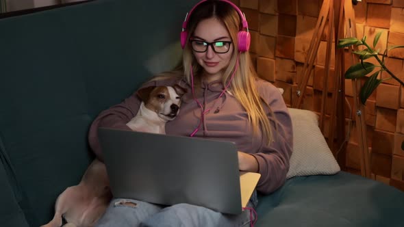 A Girl with a Dog Watching a Movie on a Laptop with Headphones