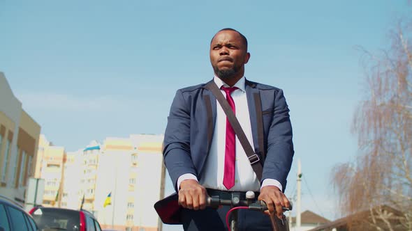 Pleasant African Businessman Driving Electric Scooter Outdoors
