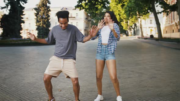 Darkskinned Male and Female are Smiling and Dancing at City Square