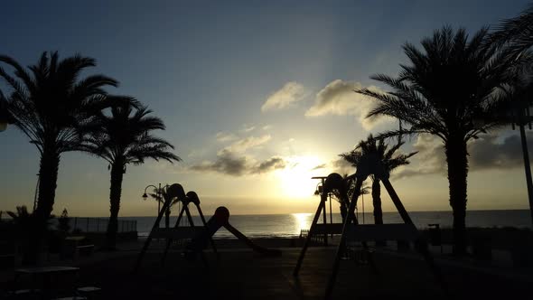 Children playground in front of the beach at sunrise time. TIMELAPSE.