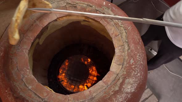 Baker making Turkish lavash in tandoor, clay oven. Baking process.