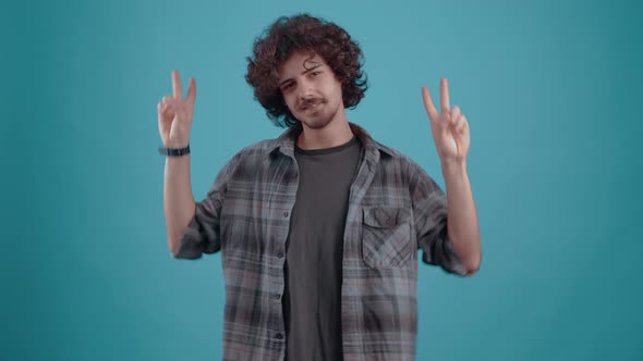 Young Hipster with the Fingers of Both Hands Shows the Sign of Peace