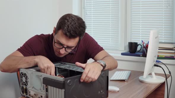Young Professional Worker Trying to Repair a Computer in the Office Using a Screwdriver and