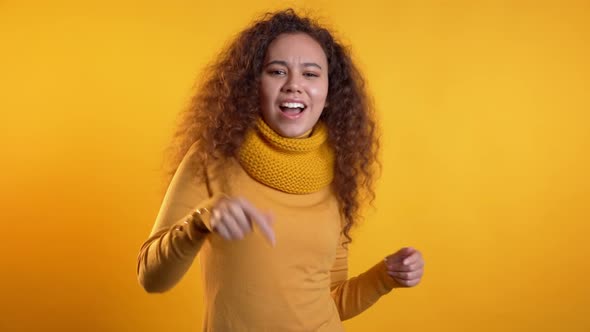 Beautiful Woman with Curly Hair Dancing with Hands on Yellow Studio 