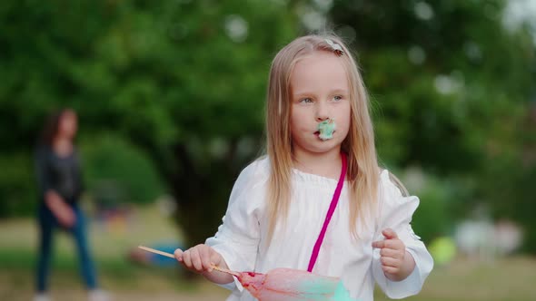 Funny little girl eats candyfloss outdoors