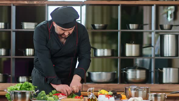 Handsome Male Chef in Black Uniform Cutting Greens and Pepper