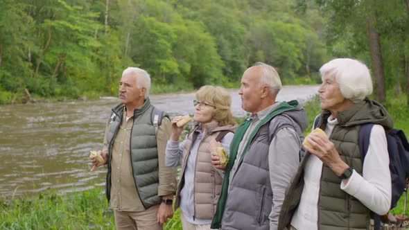 Elderly Tourists Eating Sandwiches on Riverbank