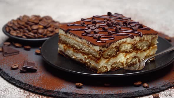 Portion of Traditional Italian Tiramisu dessert on grey concrete background