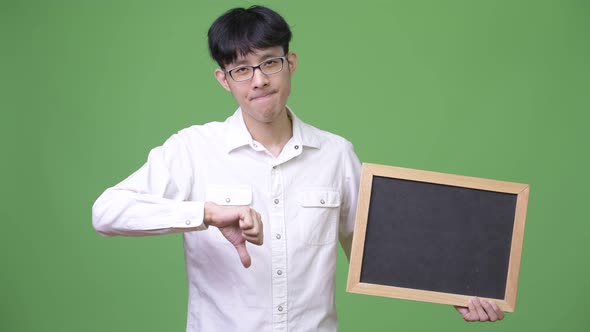Young Asian Businessman Holding Blackboard While Giving Thumbs Down