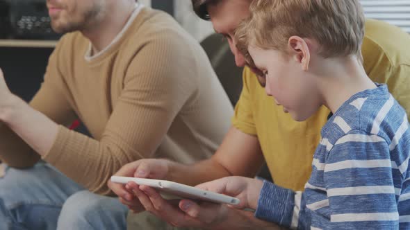 Men and Little Boy Using Mobile Phone and Tablet