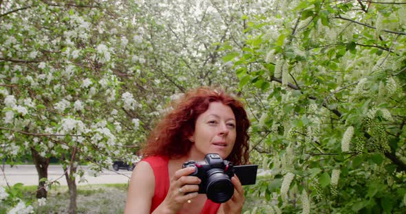 Woman Taking Pictures in a Blooming Park