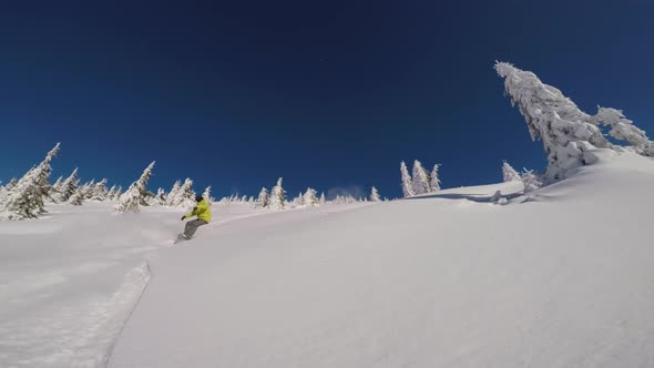 Slow Motion Tracking Shot of a Snowboarder on a Bright Sunny Day Cruising Down the Mountain with a