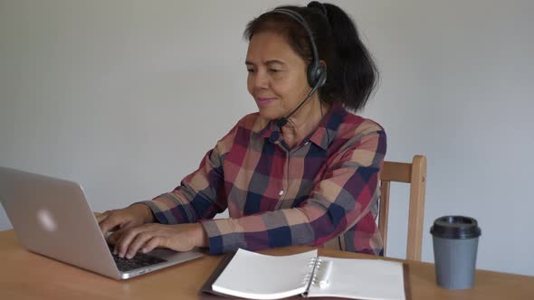 Senior Asian Call Center working at home, talking, smiling