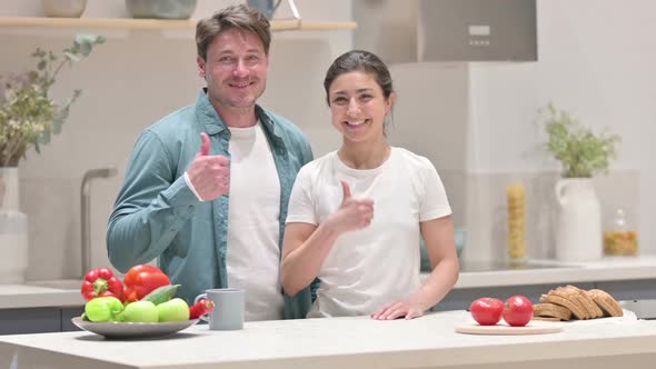 Mixed Race Couple Showing Thumbs Up Sign in Kitchen