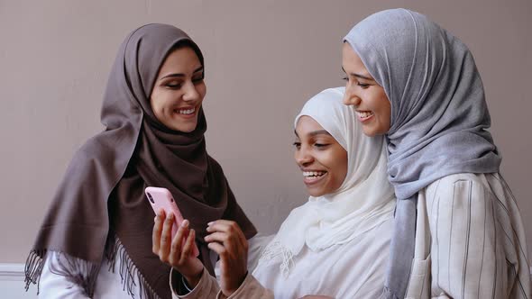 Three Muslim Girls Take Selfie on Phone Smiling and Laughing in Beige Studio