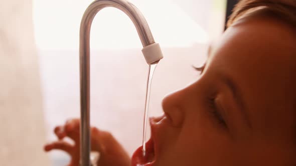 Thirsty schoolboy drinking water from faucet 4k