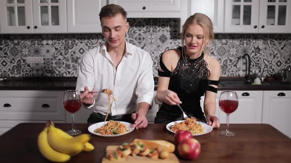 Young Couple Eating Pasta on Kitchen Table