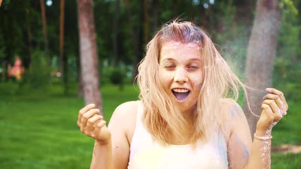 Smiling Blonde Girl Being Sprinkled with Colorful Powder at Holi Festival