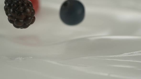 Fresh red-black raspberries and blueberries rain on yogurt in slow motion – Close up