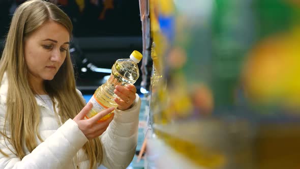 A Woman Chooses Vegetable Oil in a Supermarket