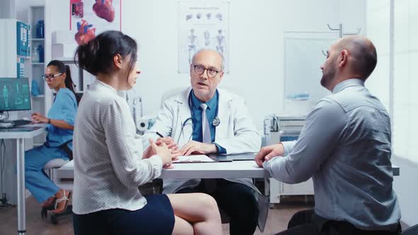 Young Couple Talking with Senior Doctor