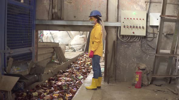 Womanworker in Yellow and Transparent Protecting Glasses Hard Hat and Mask Watching the Conveyor